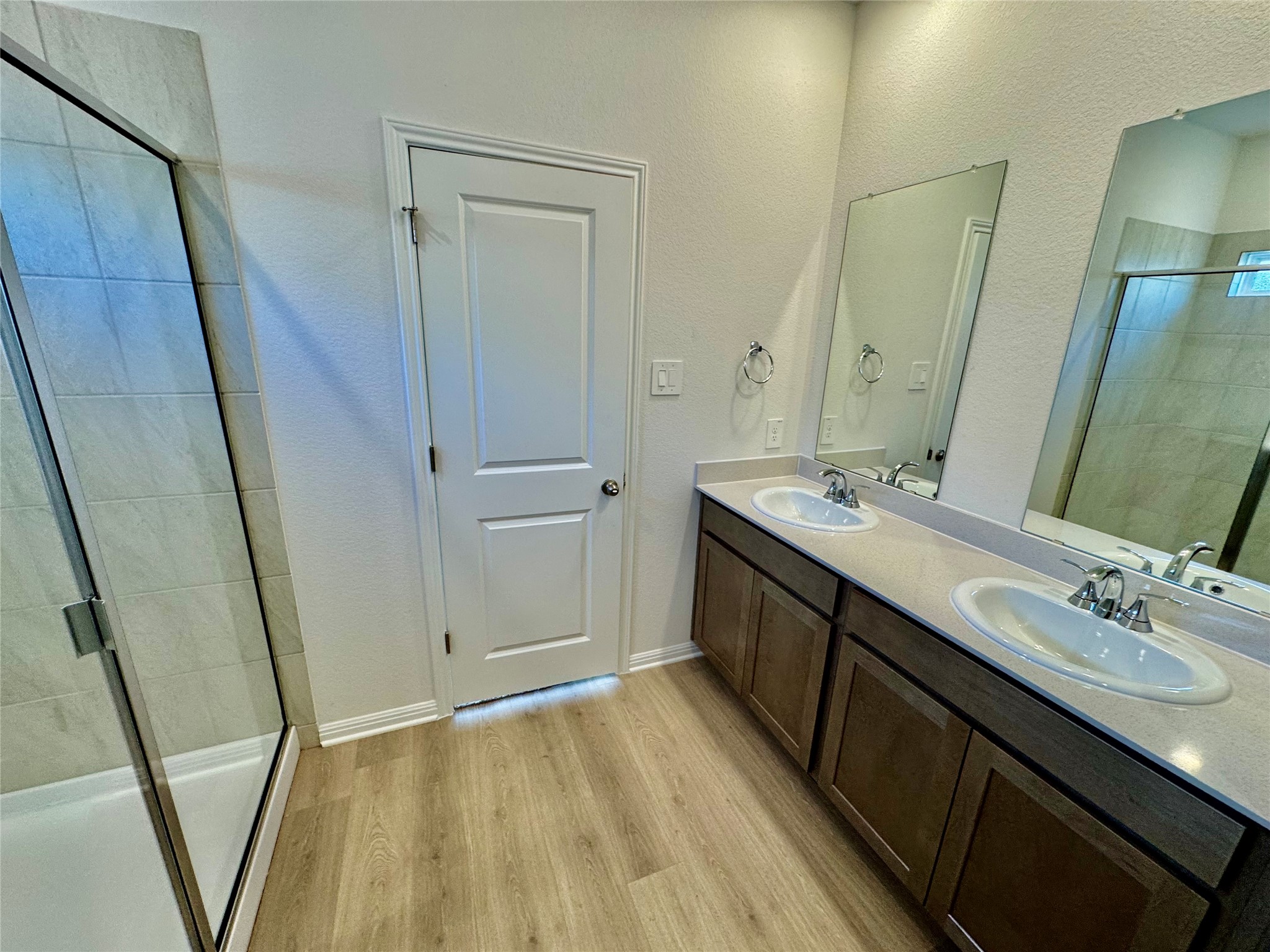 137 Boondoggle Ridge Cedar Creek, TX 78612 - Photo 4 of 7 Full bath featuring a shower stall, double vanity, light wood-type flooring, and a textured wall