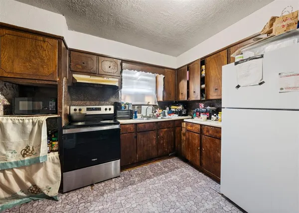 a kitchen with granite countertop a refrigerator stove top oven and sink