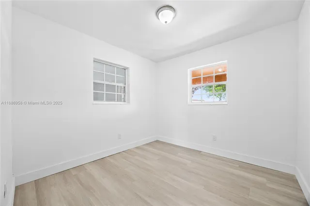 an empty room with wooden floor and window