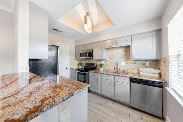 a kitchen with stainless steel appliances granite countertop a sink stove microwave and refrigerator