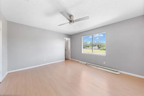 an empty room with windows and ceiling fan