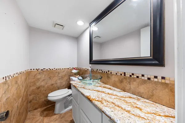 a bathroom with a granite countertop toilet sink and mirror