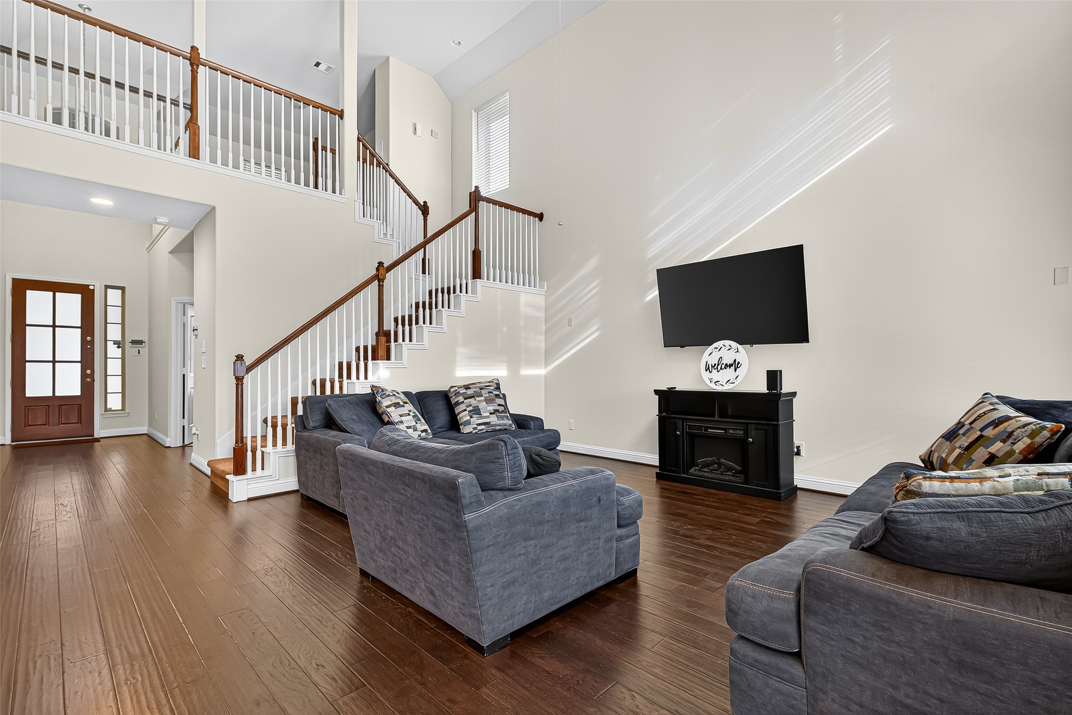 8107 Lockridge Terrace Lane Cypress, TX 77433 - Photo 9 of 50 Feel your heart soar! This stunning living room features dramatic two-story ceilings that create an incredible sense of light and space. Rich, warm flooring flows throughout, grounding the grand room with a cozy feel. The elegant, open staircase is a beautiful focal point, welcoming you into the heart of this special home.