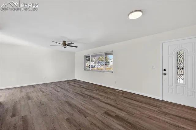 an empty room with wooden floor and windows