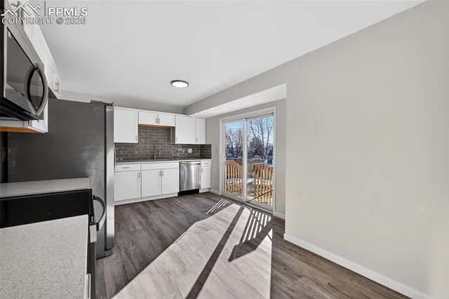 a kitchen with a refrigerator and wooden floor