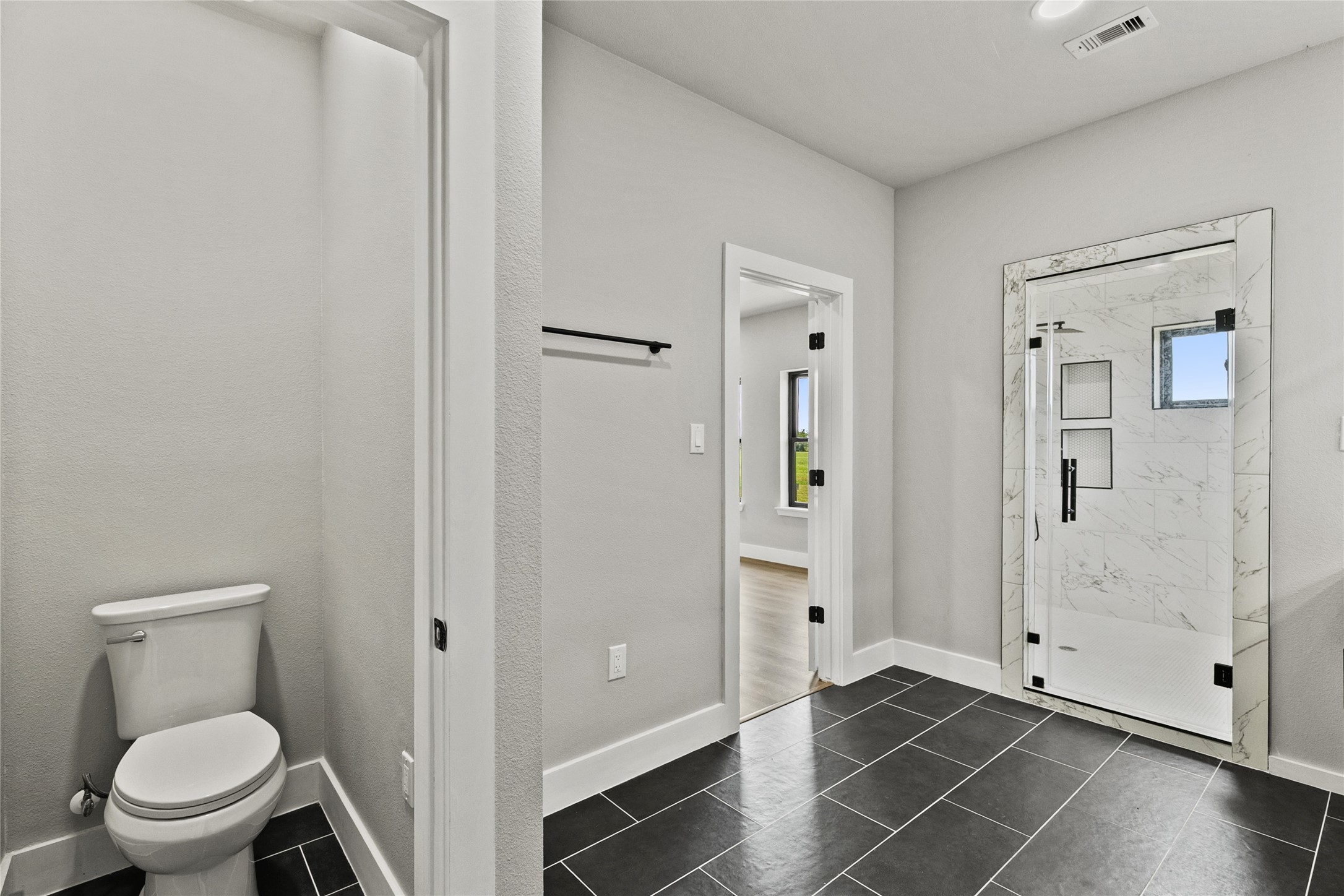 619 Chuckwagon Trail Angleton, TX 77515 - Photo 24 of 37 Spa-inspired primary bath featuring a fully tiled wet room with a freestanding soaking tub, dual shower heads, double vanities, illuminated mirror, and a private water closet. Thoughtfully designed with both style and functionality in mind.