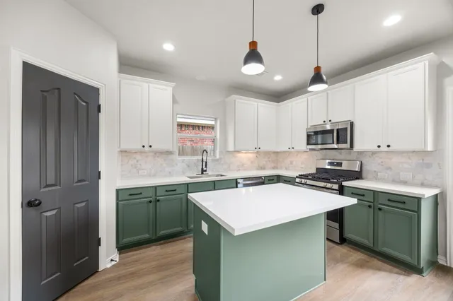 a kitchen with a sink a center island a stove cabinets and a window