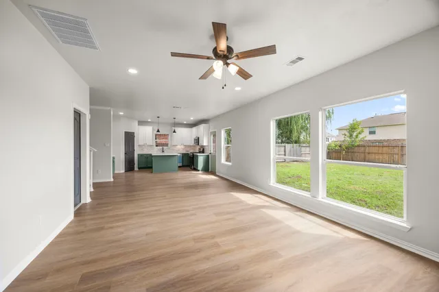 a view of empty room with wooden floor and fan