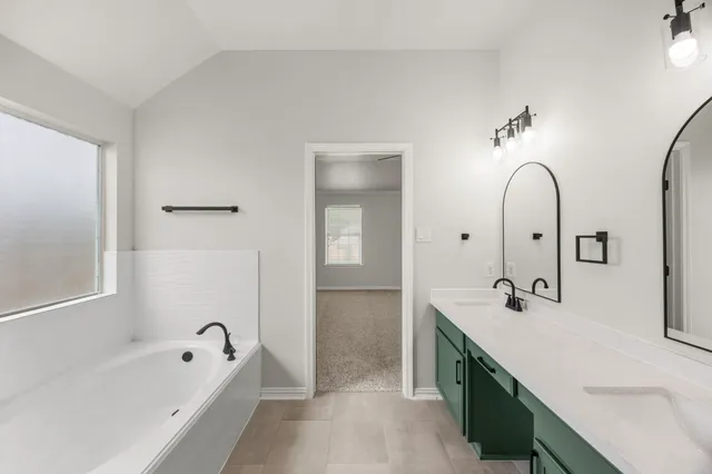 a spacious bathroom with a double vanity sink a mirror and a bathtub