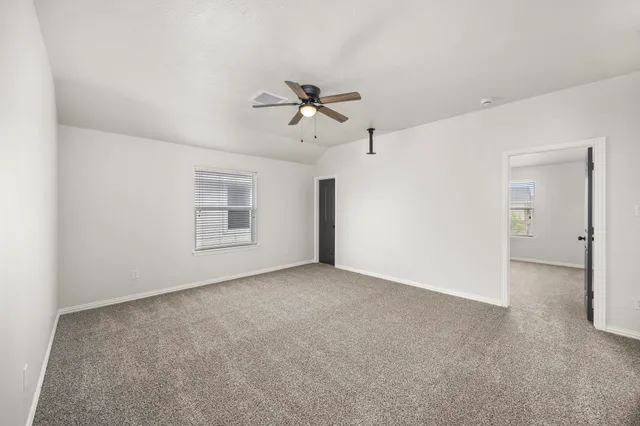 an empty room with chandelier fan and windows