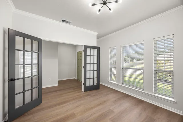 a view of an empty room with a window and wooden floor
