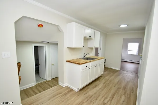 a large white kitchen with sink and wooden floor