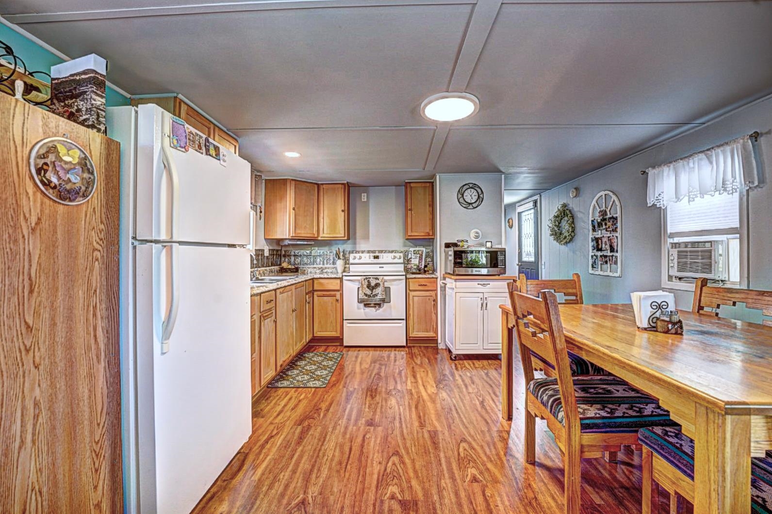 585-25 25 1/2 Road, Unit 72 Grand Junction, CO 81505 - Photo 3 of 21 a kitchen with a refrigerator a stove top oven and a dining table with wooden floor
