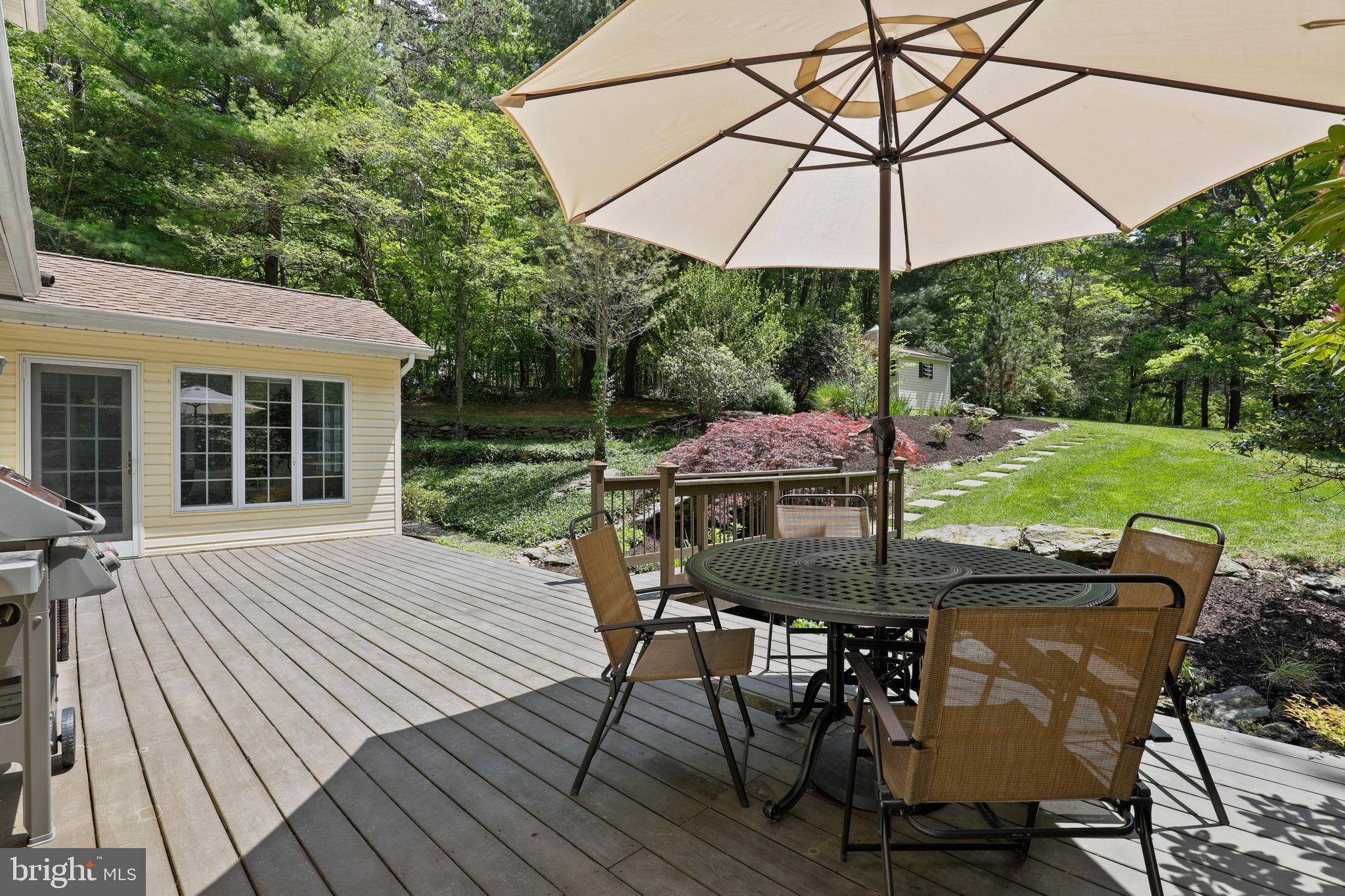 19625 Gunpowder Road Manchester, MD 21102 - Photo 34 of 44 a patio with wooden floor a yard a table and chairs under an umbrella