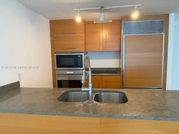 a kitchen with stainless steel appliances granite countertop a sink a oven and a refrigerator