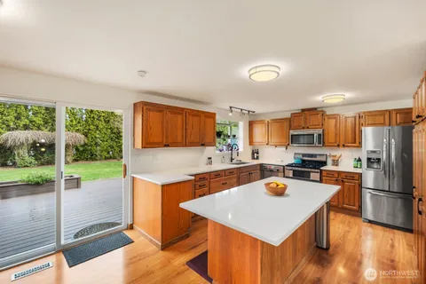 a kitchen with a stove a refrigerator and a view of living room
