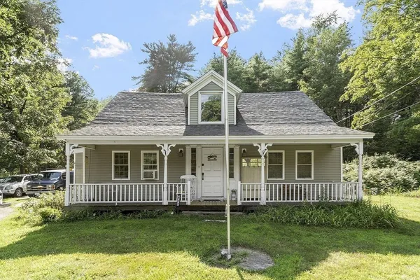 a view of a brick house with a yard and large trees