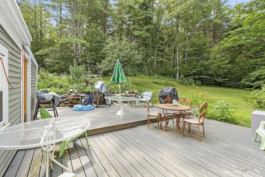 610 South Main Street Orange, MA 01364 - Photo 23 of 38 a view of a patio with dining table and chairs with wooden floor and fence