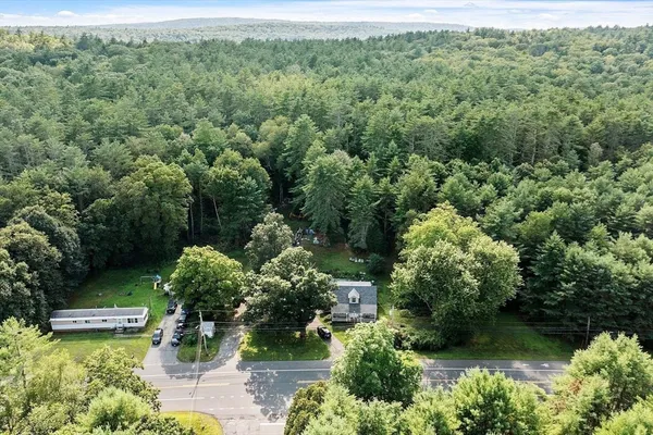 an aerial view of a house with swimming pool and trees all around