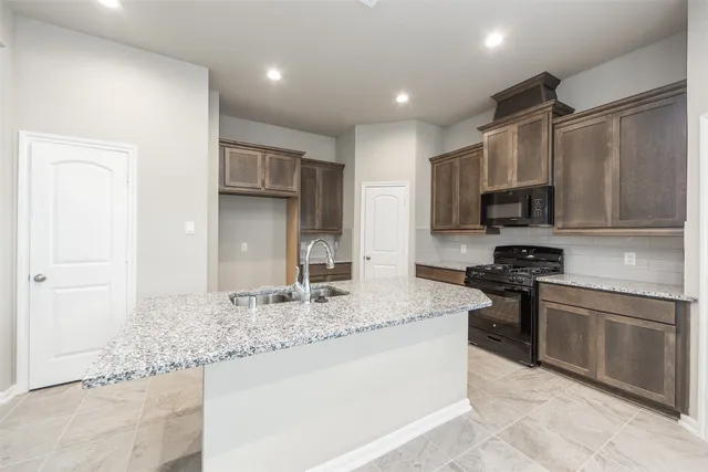 a kitchen with stainless steel appliances granite countertop a sink stove microwave and refrigerator