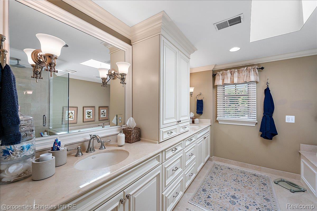 135 Clifton Road Bloomfield Hills, MI 48301 - Photo 38 of 77 Dual vanity with integrated sinks, extensive white cabinetry, large framed mirror, and a skylight