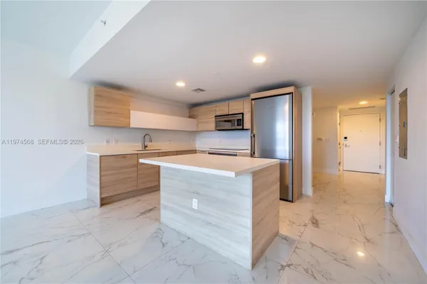 a view of kitchen with granite countertop cabinets and refrigerator