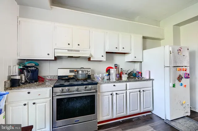 a kitchen with granite countertop a white stove a refrigerator and white cabinets