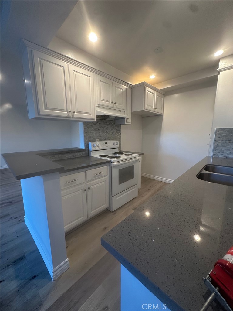 4533 Colbath Avenue, Unit 20 Sherman Oaks, CA 91423 - Photo 18 of 22 a kitchen with stainless steel appliances granite countertop a stove a sink dishwasher and a microwave with wooden floor