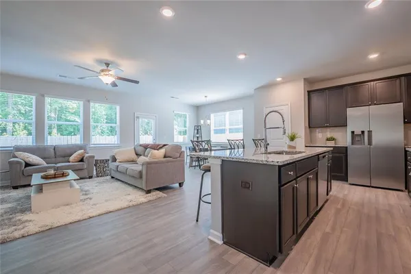 a living room with stainless steel appliances granite countertop furniture wooden floor and a large window