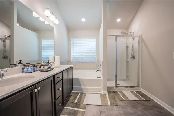 a spacious bathroom with a double vanity sink a mirror and a bathtub