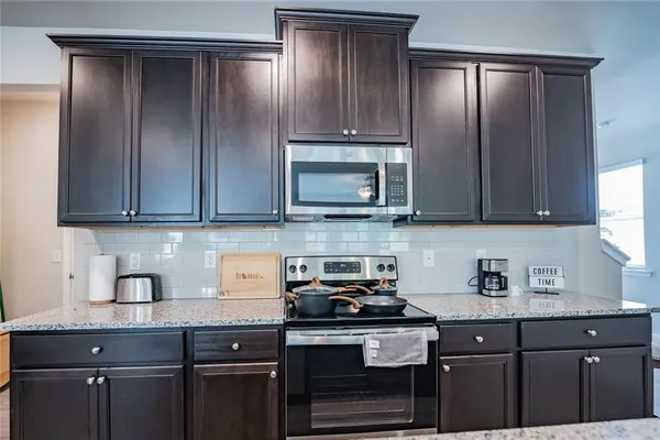 a kitchen with stainless steel appliances granite countertop a sink a stove and cabinets