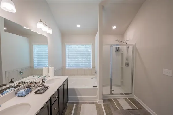 a bathroom with a tub sink double vanity and shower