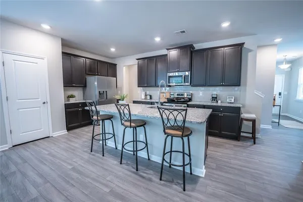 a kitchen with stainless steel appliances kitchen island granite countertop a stove a refrigerator a sink a table and chairs