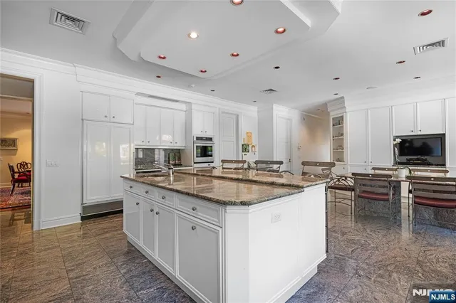 a kitchen with appliances a sink a counter and chairs