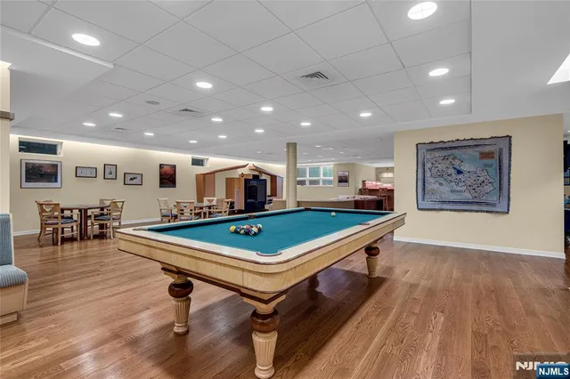 a room with wooden floor pool table and chairs