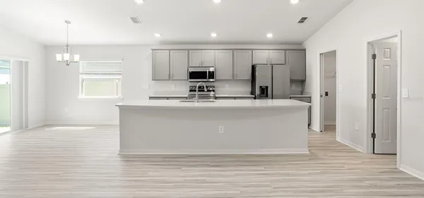 a large white kitchen with kitchen island a sink stainless steel appliances and cabinets
