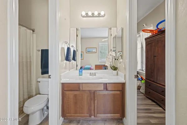 a bathroom with a granite countertop sink a toilet a mirror and shower