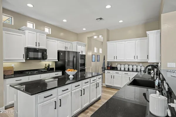 a kitchen with stainless steel appliances a stove a sink a refrigerator white cabinets and a refrigerator