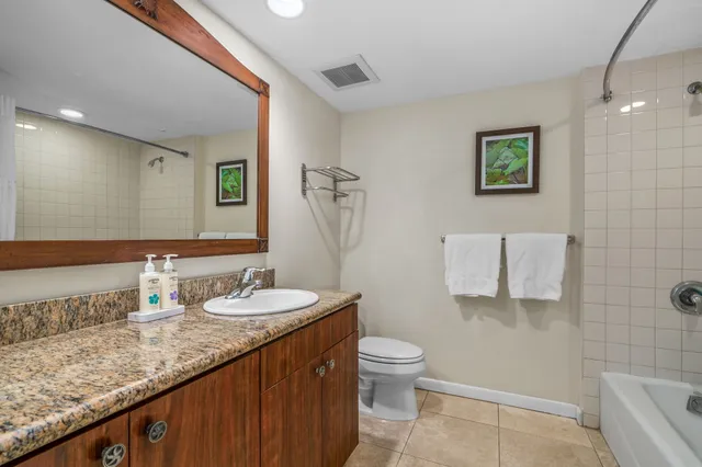 a bathroom with a granite countertop sink mirror vanity and toilet