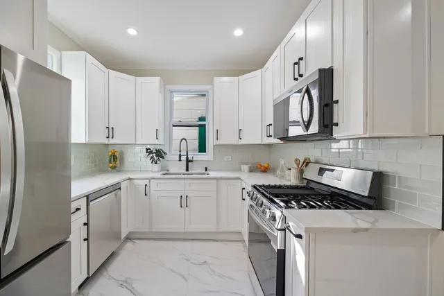 a kitchen with stainless steel appliances granite countertop a refrigerator sink and white cabinets