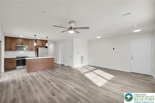 a view of kitchen with stainless steel appliances kitchen island wooden floor and window