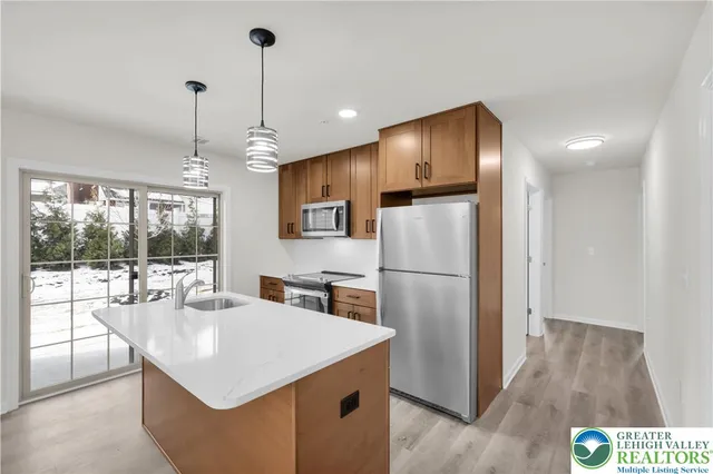 a kitchen with kitchen island a counter top space appliances and a living room view