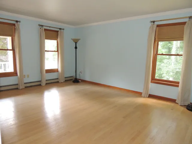 an empty room with wooden floor and windows