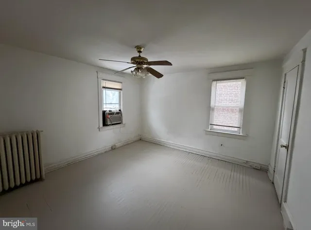 an empty room with windows and fan
