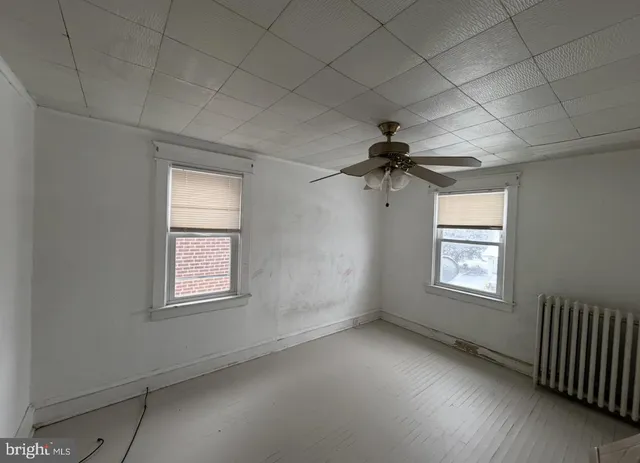 an empty room with a window and a ceiling fan
