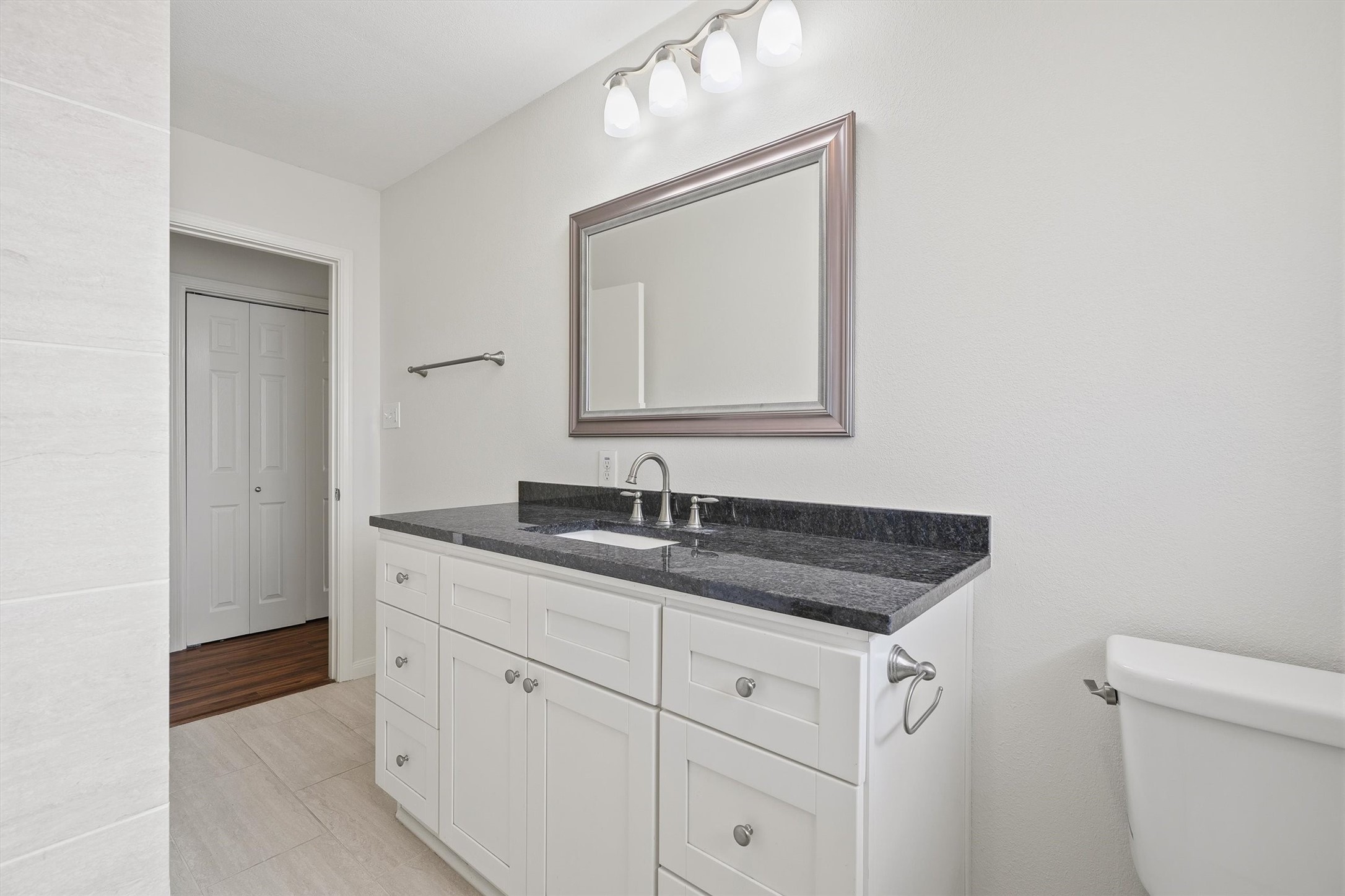 3331 Arbor Street Houston, TX 77004 - Photo 21 of 30 This area features a modern design with a sleek black countertop on a white vanity, a large framed mirror, and tile flooring. It offers ample storage and is well-lit with stylish fixtures.