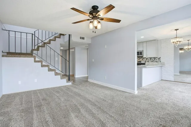 a view of an empty room and kitchen view of a house