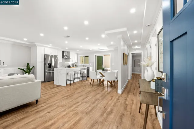 a living room with furniture and kitchen view with wooden floor