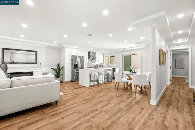 a living room with furniture a wooden floor and a kitchen view
