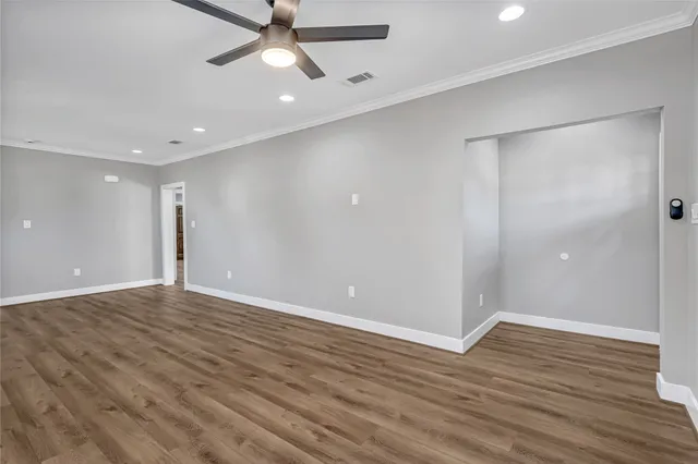 an empty room with wooden floor closet and windows